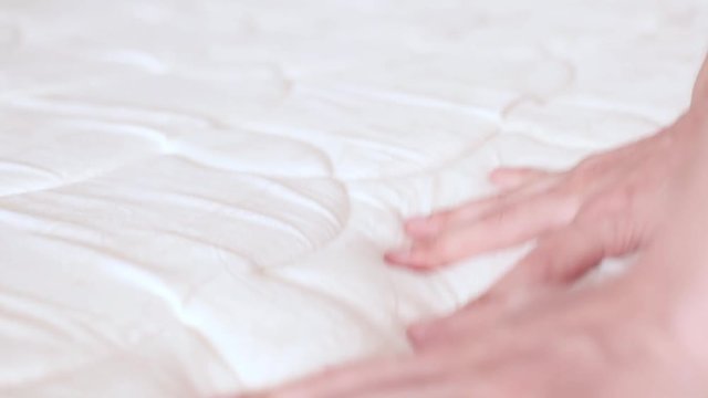 man touches the mattress on the bed