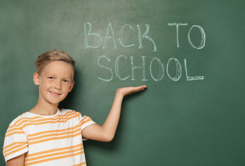 Little child near chalkboard with text BACK TO SCHOOL