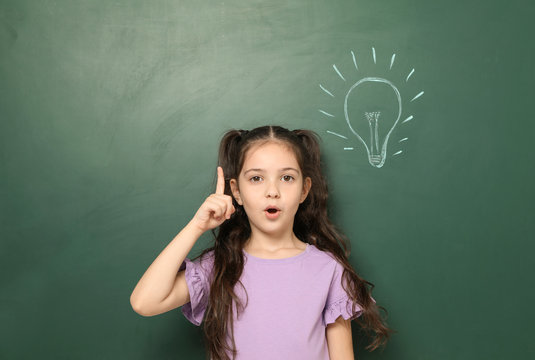 Little school child near chalkboard with lightbulb drawing