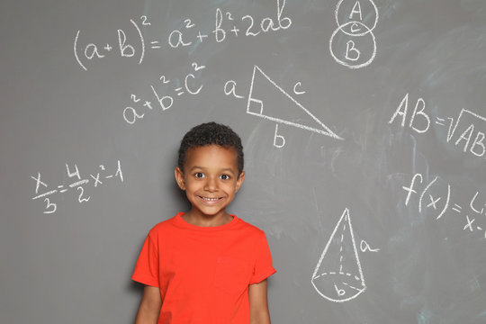 Little African-American school child and mathematical formulas on grey background