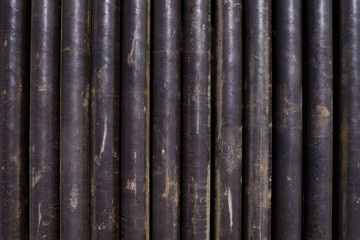 Obraz premium Oil Drill pipe. Rusty drill pipes were drilled in the well section. Downhole drilling rig. Laying the pipe on the deck. View of the shell of drill pipes laid in courtyard of the oil and gas warehouse.