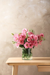 Fototapeta na wymiar Vase with beautiful Eustoma flowers on table against color background