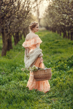 Beautiful young girl in an old dress in a pear-blossoming garden.