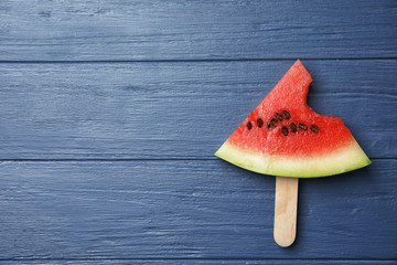 Fototapeta na wymiar Watermelon popsicle with bite mark on wooden background, top view