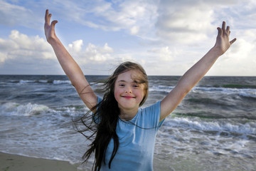 Fototapeta na wymiar Portrait of down syndrome girl smiling on background of the sea