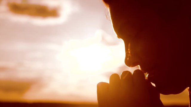 the girl prays. Girl folded her hands in prayer silhouette at sunset. slow motion video. lifestyle Girl folded her hands in prayer pray to God. girl praying asks forgiveness for sins of repentance
