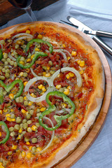 Pizza with corn, bacon, chili, onion, pea