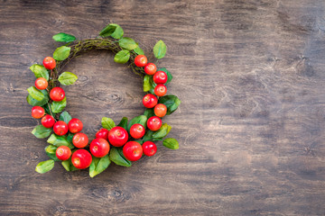 A colorful wreath of small red apples on the wooden background