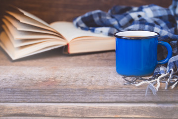 Blue cup of coffee with a knitted scarf on a wooden background