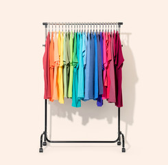 Mobile rack with color clothes on light background. File contains a path to isolation. 