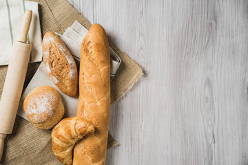 fresh bread and wheat on sack and wooden table.