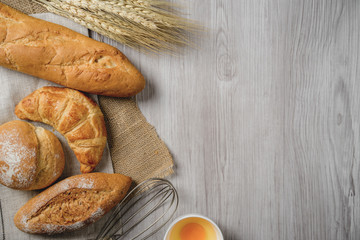 fresh bread and wheat on sack and wooden table.