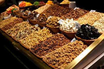 Different nuts in Wicker basket for sale at market. Display with Tasty walnut, pecan at the Boqueria market in Barcelona. Counter In Spanish Market