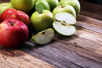 Ripe red apples with leaves on wooden background.