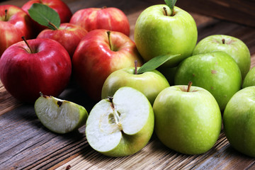 Ripe red apples with leaves on wooden background.