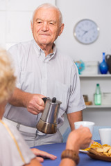 Senior man pouring coffee to female