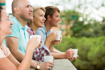 Obraz na płótnie Canvas males and females drinking coffee outdoors