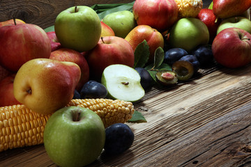 Various fresh fruits. Thanksgiving pumpkin, apples, and maize on rustic background.
