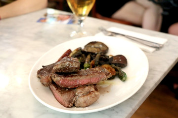Medium rare steak, served with roasted vegetables and a glass of beer. Selective focus.