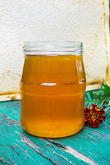 Large bee honeycomb and a jar with honey on a vintage table in front of nature.