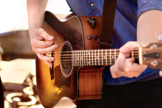 Street artist freelancer musician guy , holding concert and playing a guitar.  Man earning money on street strangers charity. Old retro acoustic quitar. 