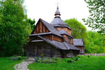 Wooden church next to beautiful green forest.