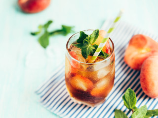 The glass of peach ice tea on wooden table. Cuba Libre or long island iced tea cocktail, cold drink...