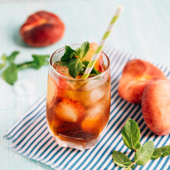The glass of peach ice tea on wooden table. Cuba Libre or long island iced tea cocktail, cold drink...