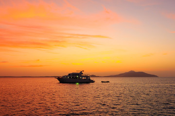 Naklejka na ściany i meble Yacht in the rays of the setting sun against the island of Tirana. Red sea. Egypt.