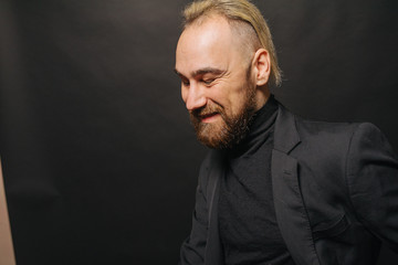 Obraz premium Elegancki przystojny mężczyzna w klasycznym garniturze pozuje w studio teatralnym.