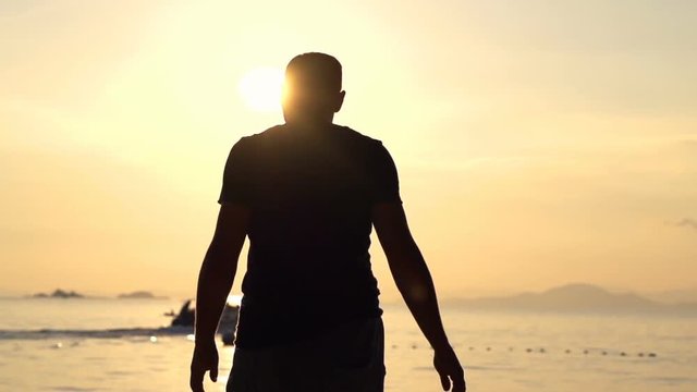 Silhouette of man walking on beach during sunset
