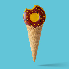 Inflatable donut pool toy with ice cream cone on pastel blue background. Minimal summer concept.