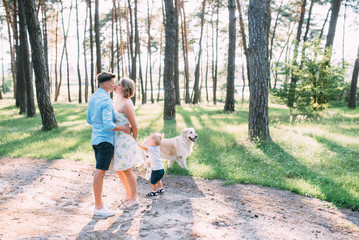 Fototapeta premium A cute family - mom, dad and son spend fun time outdoors with their dog