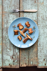 Edible forest mushrooms. Fried porcini mushrooms (Boletus edulis) on blue plate on old blue boards copyspace