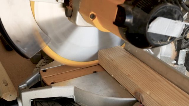 Carpenter cuts pine lumber with a miter saw - CLOSE UP