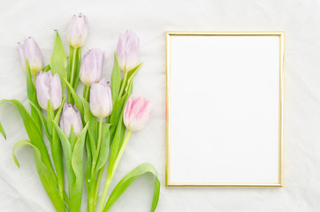 Trendy mock up with pink tulips and golden empty frame. Flat lay, top view.