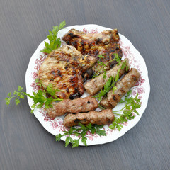 steak and chevation with a grill in a plate with parsley on a gray background table.