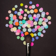 Obraz na płótnie Canvas Makeup brush with colorful confetti on black background