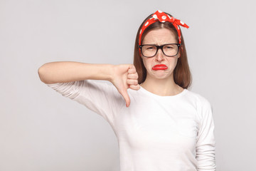 its bad, sad thumbs down of unsatisfied emotional young woman in white t-shirt with freckles, black...