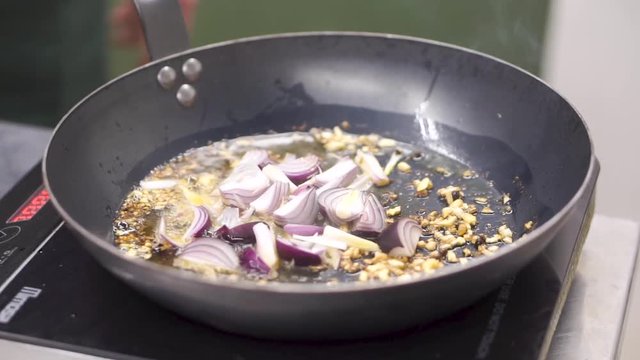 Cooking frying vegetables in wok. Clip. Chef frying chopped white onion. Chopped oning frying in pan. Steaming from pan with frying onion. Vegetables are fried in a pan