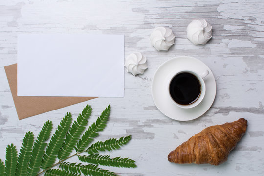 Blank page on rustic wooden background with croasant, coffee, marshmallows. Vintage mockup with text place