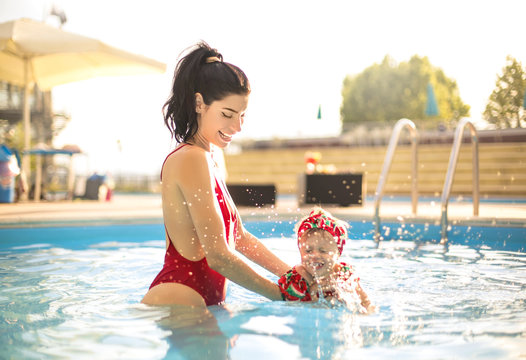 Mother and daughter having fun swimming in a swimming pool