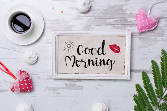Good morning lettering on rustic wooden background with croasant, coffee, marshmallows.