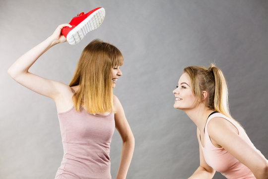 Two agressive women fighting using shoes