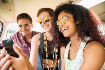 Mixed group of happy young people in a vintage van having fun 