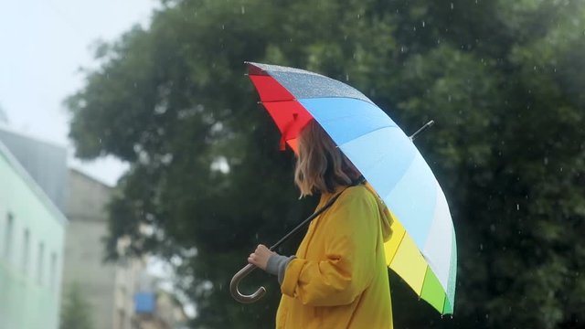 young blond stylish woman with colorful umbrella standing outside on the street rainy weather rainbow colored parasol happy lifestyle successful businesswoman walking enjoying fresh air rainstorm