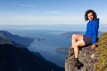 Adventurous woman is enjoying the view in the mountains during a sunny summer day. Taken on Mount Brunswick, Lions Bay, North of Vancouver, BC, Canada.