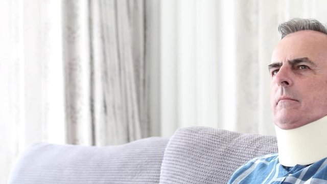 Mature Man Wearing Neck Brace Winces With Pain