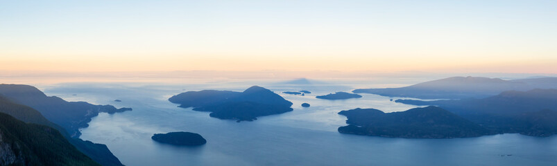 Panoramic landscape view of Howe Sound during a vibrant summer sunrise. Taken from the top of Brunswick Mountain, North of Vancouver, BC, Canada.