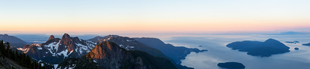 Panoramic landscape view of Howe Sound during a vibrant summer sunrise. Taken from the top of Brunswick Mountain, North of Vancouver, BC, Canada.